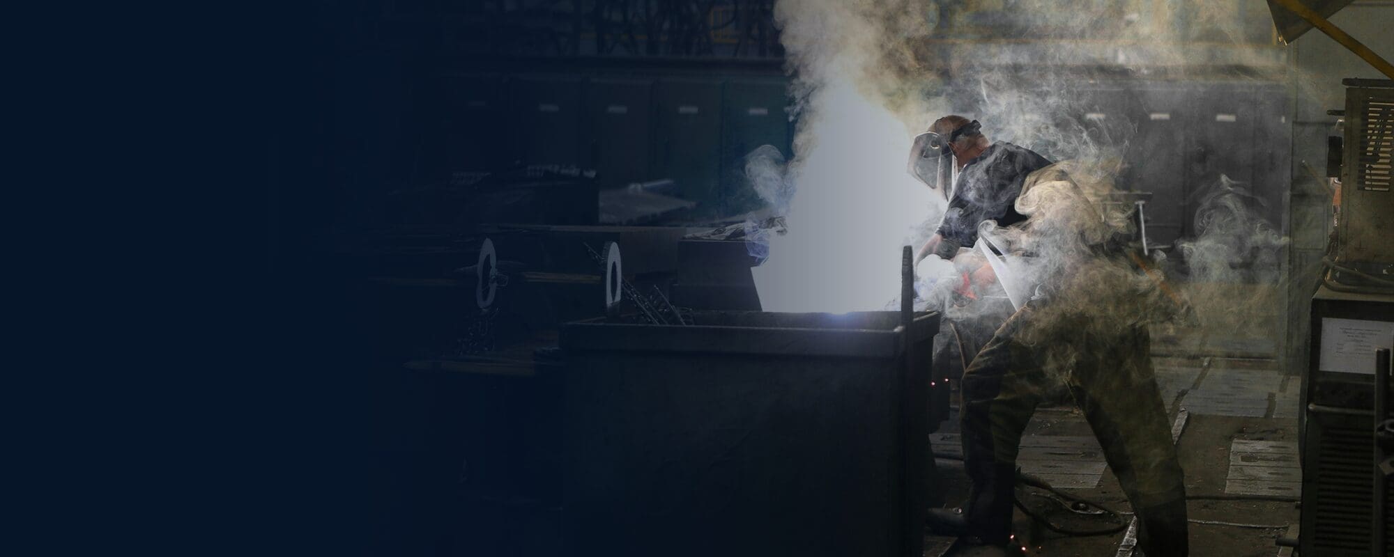 welder in dark shop making dust